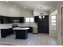 Modern kitchen featuring black cabinets, stainless steel appliances, an island and tile flooring at 15801 W Meade Ln, Goodyear, AZ 85338