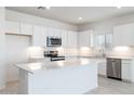 Bright, modern kitchen featuring white cabinetry, stainless steel appliances, quartz countertops, and an island at 17773 W Onyx Ave, Waddell, AZ 85355