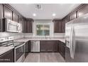 Well-equipped kitchen with stainless steel appliances, dark wood cabinets, and a window overlooking the backyard at 2547 E Vermont Dr, Gilbert, AZ 85295