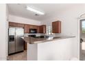 Kitchen featuring wood cabinetry, stainless steel refrigerator, and serving bar at 336 N 168Th Dr, Goodyear, AZ 85338