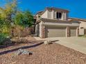 Charming beige two-story home with a three-car garage and desert landscaping in the front yard at 3634 N Desert Oasis --, Mesa, AZ 85207