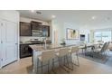 Modern kitchen with dark cabinets, granite countertops, stainless steel appliances, and an island with seating at 40060 W Wade Dr, Maricopa, AZ 85138