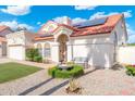 Inviting single-story home featuring a manicured yard, red tiled roof, and solar panels at 7503 W Julie Dr, Glendale, AZ 85308