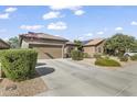 Beautiful home exterior featuring manicured shrubs, desert landscaping, and a spacious driveway at 10749 W Lariat Ln, Peoria, AZ 85383