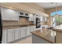 Bright kitchen with white cabinetry, modern appliances, granite countertops, and a sink under a large window at 10936 N Ventana W Dr, Peoria, AZ 85373