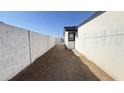 A long, narrow side yard features a block wall, dirt landscape, and access to the backyard at 121 E Monte Way, Phoenix, AZ 85042