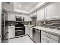 Updated kitchen features stainless steel appliances, white cabinets, and stylish backsplash and countertop at 7970 E Camelback Rd # 101, Scottsdale, AZ 85251