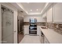 Modern kitchen featuring stainless steel appliances, sleek white cabinetry, and a tiled backsplash at 7970 E Camelback Rd # 101, Scottsdale, AZ 85251