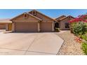 Home exterior featuring a three-car garage, desert landscaping, and a well-maintained front yard with mature flowering bushes at 10931 N 129Th Way, Scottsdale, AZ 85259