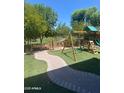Spacious backyard featuring a curved walkway, artificial grass, trees, and a playset at 2018 W Marconi Ave, Phoenix, AZ 85023