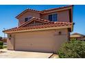 Home exterior showcasing a two-car garage, complemented by a red-tiled roof and low landscape at 22322 W Loma Linda Cir, Buckeye, AZ 85326