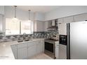 Updated kitchen features stainless steel appliances, mosaic backsplash, granite countertops, and modern cabinetry at 4437 E Villa Theresa Dr, Phoenix, AZ 85032