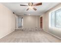 Open living room with neutral walls, carpeted flooring, a ceiling fan, and natural light from the window at 4740 W Bloomfield Rd, Glendale, AZ 85304
