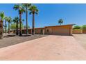 Single-story home with a two-car garage and desert landscaping with many palm trees at 7101 E Cholla St, Scottsdale, AZ 85254
