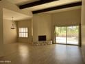 Open-concept living room with stone fireplace, beamed ceilings and sliding glass door to backyard at 8947 N 84Th Way, Scottsdale, AZ 85258