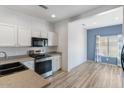 Bright kitchen featuring white cabinets, stainless steel appliances, and wood-look floors at 13796 W Mauna Loa Ln, Surprise, AZ 85379