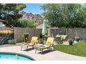 Serene backyard featuring a sparkling blue pool, lounge chairs, and lush green landscaping with mountain views at 2301 E Sunnyside Dr, Phoenix, AZ 85028