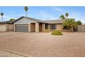 Charming brick home with a gray garage door, a desert landscape, and mature palm trees at 3106 S Extension Rd, Mesa, AZ 85210