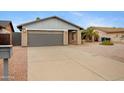 Charming brick home with a gray garage door, desert landscape, and mature palm trees at 3106 S Extension Rd, Mesa, AZ 85210