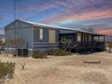 A single-story home with a covered porch, desert landscape, and cooling unit at 50525 W Whirly Bird Rd, Maricopa, AZ 85139