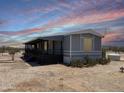 A single-story home featuring a covered porch and desert landscaping with beautiful desert sunsets at 50525 W Whirly Bird Rd, Maricopa, AZ 85139