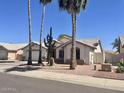 Charming single-story home with well-maintained landscaping, mature palm trees, and a desert-friendly yard at 8759 W Port Au Prince Ln, Peoria, AZ 85381