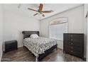Simple bedroom with dark wood floors, fan, and a window letting in natural light at 10961 W Chase Ln, Avondale, AZ 85323