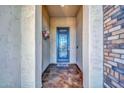 Covered entryway featuring a decorative metal and glass front door, brick accents, and neutral paint at 16961 W Holly St, Goodyear, AZ 85395