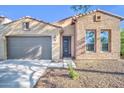 Charming brick and stucco home featuring a gray garage door, desert landscaping, and tile roof at 16961 W Holly St, Goodyear, AZ 85395