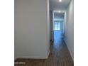 Bright hallway with wood-look tile flooring and recessed lighting leading towards a sliding glass door at 18248 W La Senda Dr, Surprise, AZ 85387