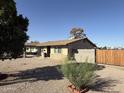 Exterior shot of a single-story home with desert landscaping and a wooden gate at 1841 N Wilbur Cir, Mesa, AZ 85201