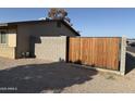 Side yard featuring gravel, a modern wooden gate, and partial view of home exterior at 1841 N Wilbur Cir, Mesa, AZ 85201