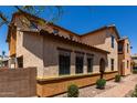 Side of a tan stucco house with a tiled roof, paver walkway, desert landscaping, and green shrubs at 4745 W Fremont Rd, Laveen, AZ 85339
