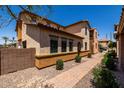 Side of a tan stucco house with a tiled roof, paver walkway, desert landscaping, and green shrubs at 4745 W Fremont Rd, Laveen, AZ 85339