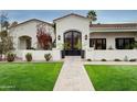 Up close front exterior showcasing desert landscaping, grass lawn and an arched entry with glass doors at 8045 E Del Caverna Dr, Scottsdale, AZ 85258