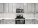 Modern kitchen featuring stainless steel microwave and electric stove complemented by grey cabinets at 14870 W Encanto Blvd # 1059, Goodyear, AZ 85395