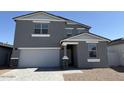 Two-story home with a gray exterior, paved driveway, attached two-car garage, and desert landscaping at 18265 W La Senda Dr, Surprise, AZ 85387