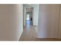 Bright hallway with wood-look tile flooring leading to the kitchen and a sliding glass door at 18265 W La Senda Dr, Surprise, AZ 85387