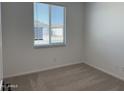A cozy bedroom with neutral carpet and a bright window at 18271 W La Senda Dr, Surprise, AZ 85387
