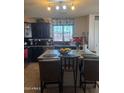 Well-lit kitchen featuring dark cabinets, granite counters, and a convenient breakfast bar at 23890 W Twilight Trl, Buckeye, AZ 85326