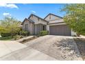 Attractive single-story home with a two-car garage, paver driveway, stone accents, and desert landscaping at 26943 N 74Th Ave, Peoria, AZ 85383