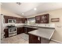 Well-lit kitchen featuring stainless steel appliances, dark wood cabinetry and light countertops at 5127 E Tamblo Dr, Phoenix, AZ 85044