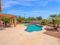 Backyard pool features a covered patio with seating, desert landscaping, and a privacy fence at 981 N Quail Ln, Gilbert, AZ 85233