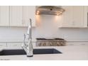 Close up on sink in modern kitchen with white cabinetry, granite counters and stainless gas range at 10013 S 36Th Ave, Laveen, AZ 85339