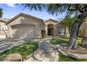 Daytime shot of a single-story home featuring a stone walkway, two car garage, and mature landscaping at 10141 E Floriade Dr, Scottsdale, AZ 85260