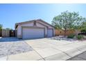 Exterior view of a home featuring a spacious three-car garage, with a desert landscaped front yard and blue skies at 14938 W Mauna Loa Ln, Surprise, AZ 85379