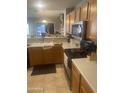 Kitchen showcasing oak cabinets, tiled flooring and stainless steel appliances at 14938 W Mauna Loa Ln, Surprise, AZ 85379