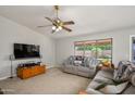 Bright living room featuring cozy seating, a ceiling fan, and a large window with views of the well-kept backyard at 14938 W Mauna Loa Ln, Surprise, AZ 85379