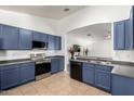 Modern kitchen with blue cabinets, stainless steel appliances, tile flooring and an open layout, perfect for cooking at 16526 W Desert Ln, Surprise, AZ 85388