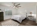 Cozy bedroom with plush carpeting, white walls, a ceiling fan, a large window and comfortable furnishings at 16526 W Desert Ln, Surprise, AZ 85388